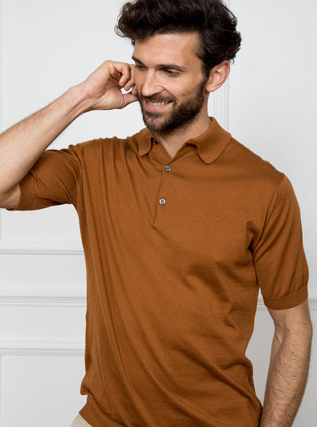 Man wearing ginger/burnt orange short sleeved polo sweater knit in 100% luxury and premium merino wool.